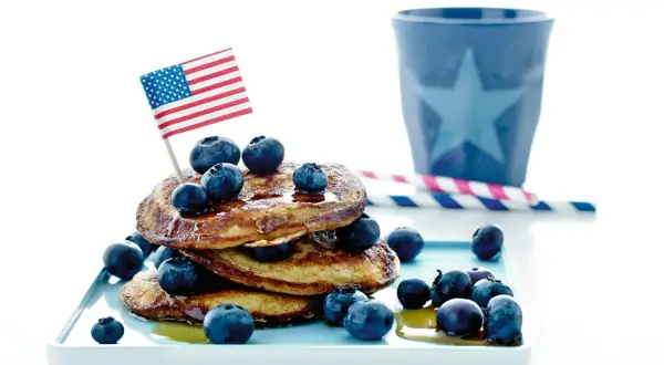 En stapel pannkakor med blåbär och en amerikansk flagga. Perfekt för att frysa pannkakor och njuta av en amerikansk frukost.