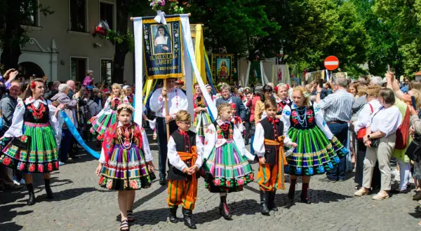 Dzieci w łowickich strojach ludowych idą w procesji Bożego Ciała. Warto uczestniczyć w procesjach Bożego Ciała w Łowiczu i okolicach, by podziwiać te barwne tradycje.