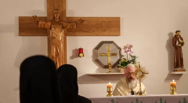 Ksiądz z brodą odprawia nabożeństwo w pierwszy czwartek miesiąca. Widać krzyż, figurę świętego i monstrancję.