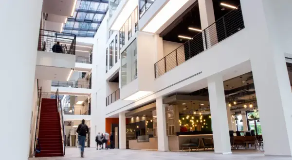 Helles, modernes Gebäude mit Glasdach und roten Treppen. Menschen gehen durch die Lobby des ISM Frankfurt.