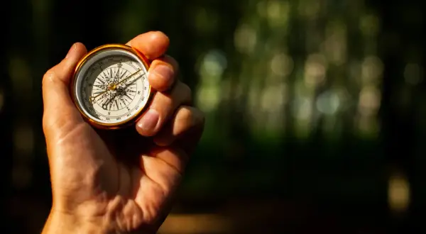 Eine Hand hält einen Kompass, der zeigt, wie funktioniert ein Kompass. Die Nadel zeigt nach Norden.