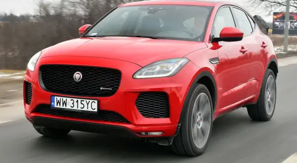 Czerwony Jaguar E-Pace pędzi po drodze, ukazując swoje sportowe linie i charakterystyczny grill.
