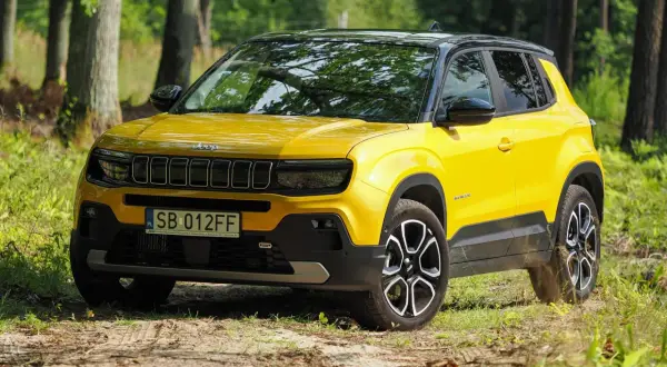 Żółty Jeep Avenger na leśnej drodze. Wiele pozytywnych jeep avenger opinie potwierdza jego miejski charakter i stylowy wygląd.