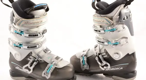 Botas de esquí Nordica para mujer, blancas y negras, con hebillas plateadas y detalles en azul.