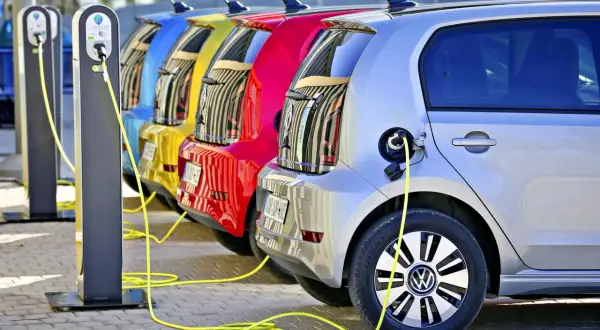 Kolorowe samochody elektryczne w Polsce ładowane na stacji.