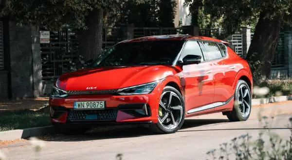 Czerwone Kia EV6 GT, gotowe do sprintu 0-100 km/h, zaparkowane przy ulicy w słoneczny dzień.