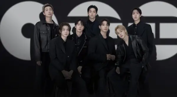 Die Mitglieder von BTS posieren in schicken schwarzen Outfits vor einem großen, stilisierten "GQ"-Logo.