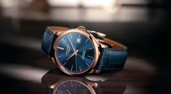 Elegancki zegarek damski rose gold z granatową tarczą i skórzanym paskiem, odbijający się w błyszczącej powierzchni.