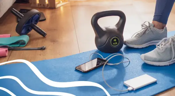 Gotowy sprzęt do treningu: hantle, gumy, rolka, mata, telefon i powerbank. Idealne warunki do cardio w domu.