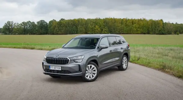 Szary Skoda Kodiaq hybryda na tle jesiennego krajobrazu.