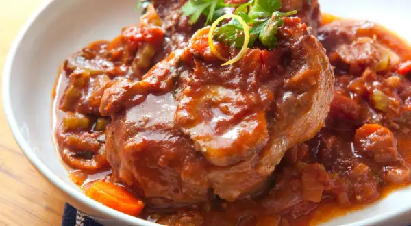 Herzhaftes Ossobuco Rezept in Tomatensoße mit Karotten und Petersilie, serviert in einer weißen Schüssel.
