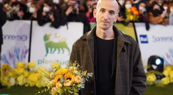 Un uomo con un mazzo di fiori, forse pensando ai testi di Fabrizio De André nella sua ora di libertà.