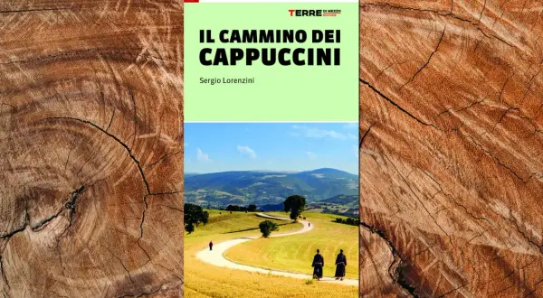 Copertina del libro "Il Cammino dei Cappuccini", con due frati che percorrono un sentiero tra colline verdi e dorate.