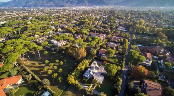 Vasta area residenziale con ville immerse nel verde, ideale per chi desidera comprare e vendere case in un contesto tranquillo con montagne sullo sfondo.