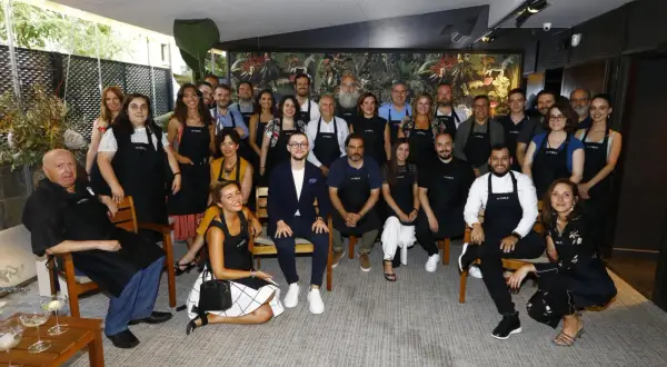 Grupo diverso posa con delantales "es.table Zaragoza" en un evento.