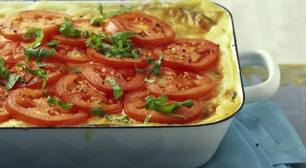 Herzhafte auberginen lasagne, überbacken mit Tomatenscheiben und frischem Basilikum, duftet verführerisch.