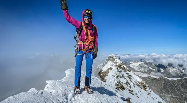 Erfolgreiche Bergsteigerin jubelt auf dem schneebedeckten Matterhorn Gipfel.