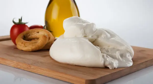 La burrata, un tesoro cremoso, si presenta su un tagliere con pomodorini, taralli e olio d'oliva.