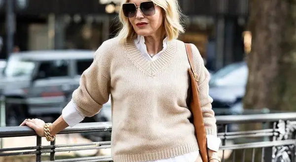 Eleganckie zestawy ubrań dla 50-latki: beżowy sweter, biała koszula i brązowa torebka. Stylowa kobieta w modnej stylizacji.