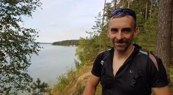 Uśmiechnięty rowerzysta na tle malowniczego zalewu sulejowskiego. Trasa rowerowa wokół zalewu sulejowskiego oferuje piękne widoki.
