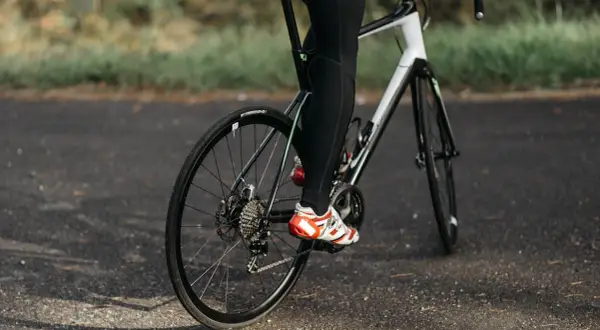 Rowerzysta w sportowych butach pedałuje, utrzymując optymalną kadencję rower.