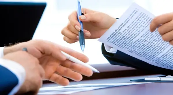 Dwie osoby analizują dokument, omawiając informację o warunkach zatrudnienia.