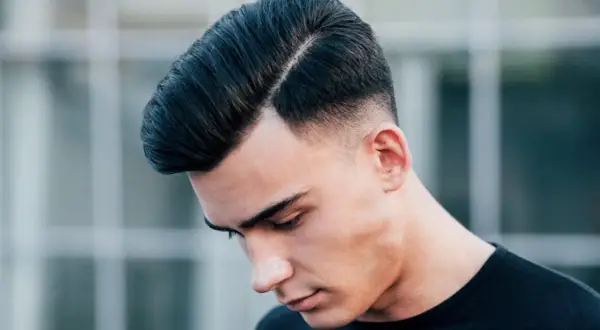 Ein Mann mit einem modernen Undercut für Herren, die Haare zur Seite gescheitelt und am Hinterkopf kurz rasiert.