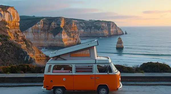 Un camping-car orange avec toit relevable sur une falaise portugaise. Idéal pour un budget pour aller au Portugal en camping-car.