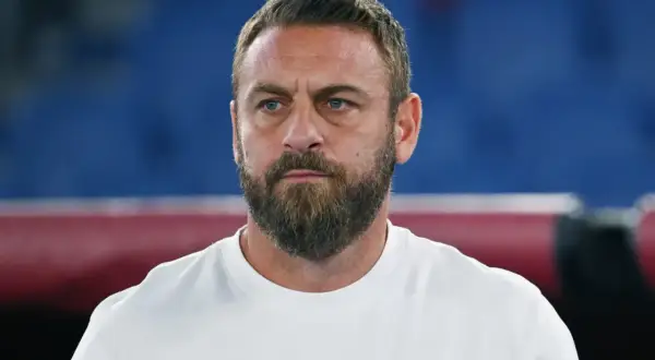 Close-up of a man with a beard and blue eyes wearing a white t-shirt.