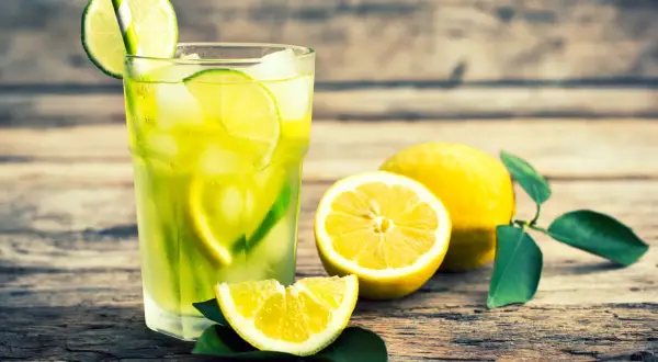 Vaso de limonada refrescante con rodajas de lima y limón, mostrando la diferencia entre lima y limón.