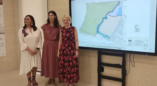 Tres mujeres observan un plano en pantalla grande, posiblemente sobre el proyecto **el toyo Almería**.