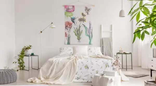 Sypialnia w stylu shabby chic z pościelą w kwiaty, narzutą i obrazem z ptakami i kwiatami.