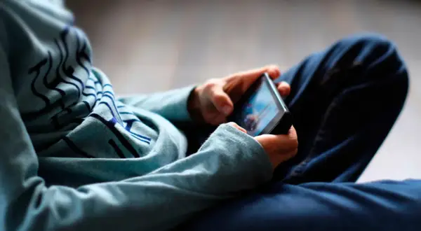 Ein digitaler Mensch, vertieft in sein Smartphone. Die Hände halten das Gerät, während der Blick auf den Bildschirm gerichtet ist.
