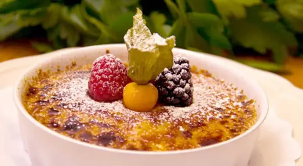 En krämig crema catalana toppad med bär och pudrat socker, en ljuvlig dessert.