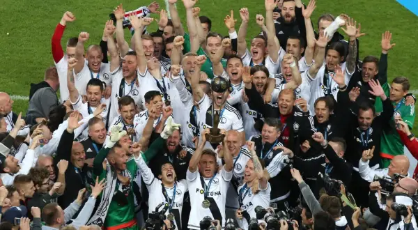 Piłkarze Legii świętują zdobycie kolejnego trofeum, podnosząc puchar. Ile mistrzostw Polski ma Legia? Tyle, ile radości na ich twarzach!