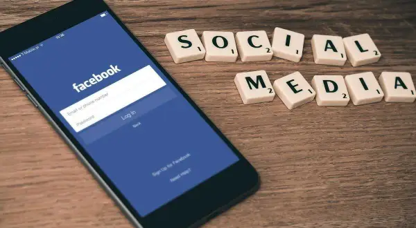 Smartfon z ekranem logowania Facebooka i kafelki z napisem "SOCIAL MEDIA".