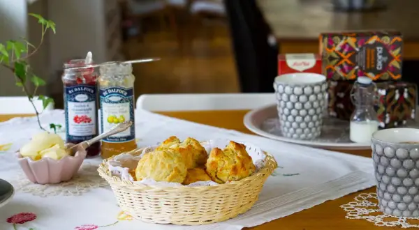 En härlig eftermiddagste med nybakade scones, sylt, smör och te.