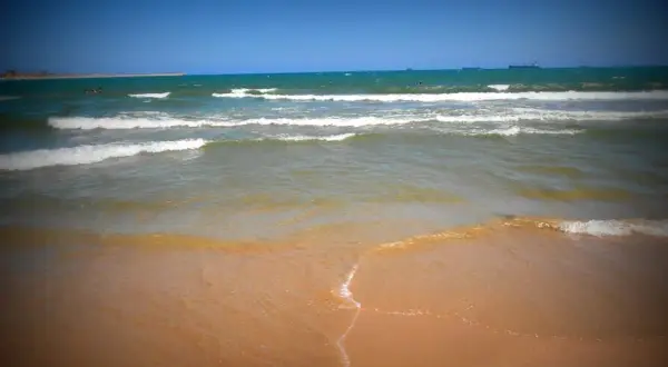 Olas rompiendo en la arena dorada, un día soleado perfecto para visitar la playa más cercana a Toledo.