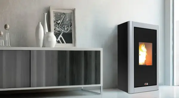 Stufa a pellet 12 kw quanti mq riscalda? Immagine di un moderno soggiorno con stufa a pellet accesa, mobile contenitore e decorazioni.