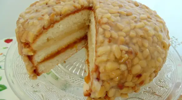 Tarta de piñones tradicional, con capas de bizcocho y mermelada, cubierta de piñones caramelizados. ¡Un dulce irresistible!