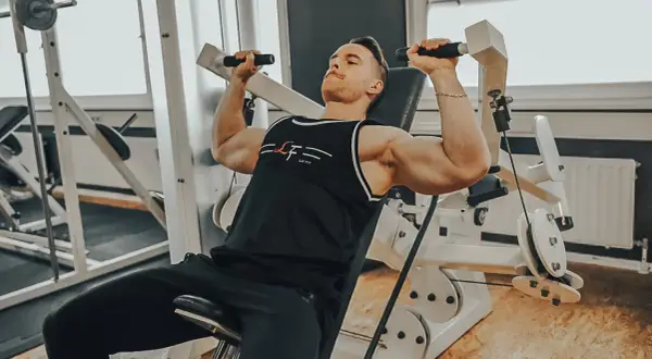 Mann trainiert Schultern an einer Maschine, ein intensiver superset workout für maximale Ergebnisse.