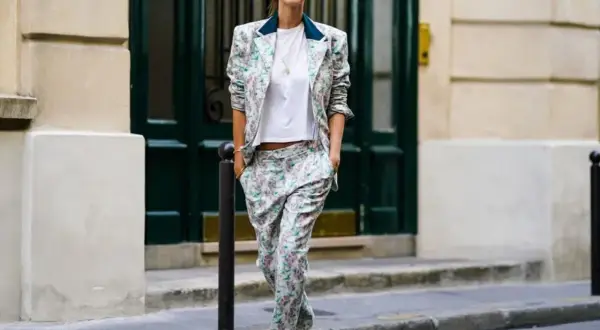 Donna con tailleur floreale e scarpe basse cammina per strada, con un'aria disinvolta e chic.