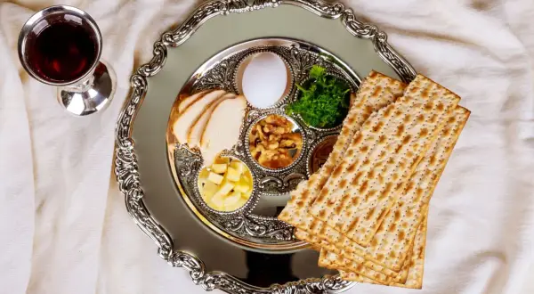 Talerz z symbolami jedzenia koszernego na Pesach: macą, jajkiem, warzywami i mięsem. Obok kielich z winem.