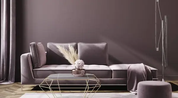 Ein luxuriöses Sofa in Mauve-Farbe mit einem geometrischen Couchtisch und einem runden Hocker.