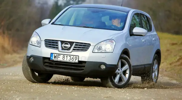 Srebrny Nissan Qashqai 2.0 benzyna na drodze szutrowej, kierowca za kierownicą.