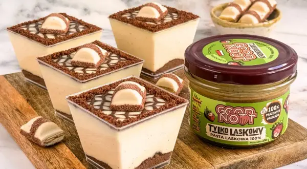 Mini deserki czekoladowe z kremem i kawałkami batonika, obok słoik pasty z orzechów laskowych.