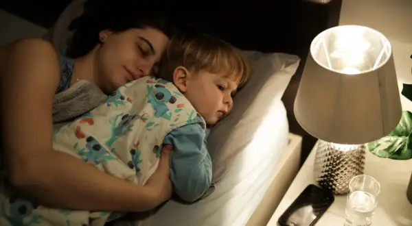 Mamma e figlio dormono abbracciati a letto, avvolti in una coperta con koala. Un momento di pace prima che i miei figli si sveglino.