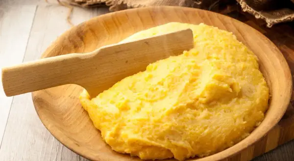 Gorąca polenta, czyli co to jest? Aromatyczna, żółta kaszka kukurydziana podana w drewnianej misie, gotowa do jedzenia.