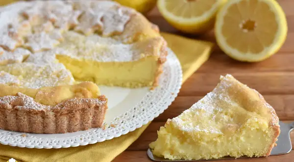 Una fetta di crostata al limone, cosparsa di zucchero a velo, pronta per essere gustata.