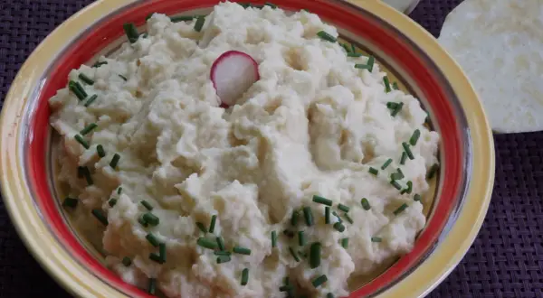 Puszyste puree z selera, udekorowane szczypiorkiem i plasterkiem rzodkiewki, prezentuje się apetycznie.